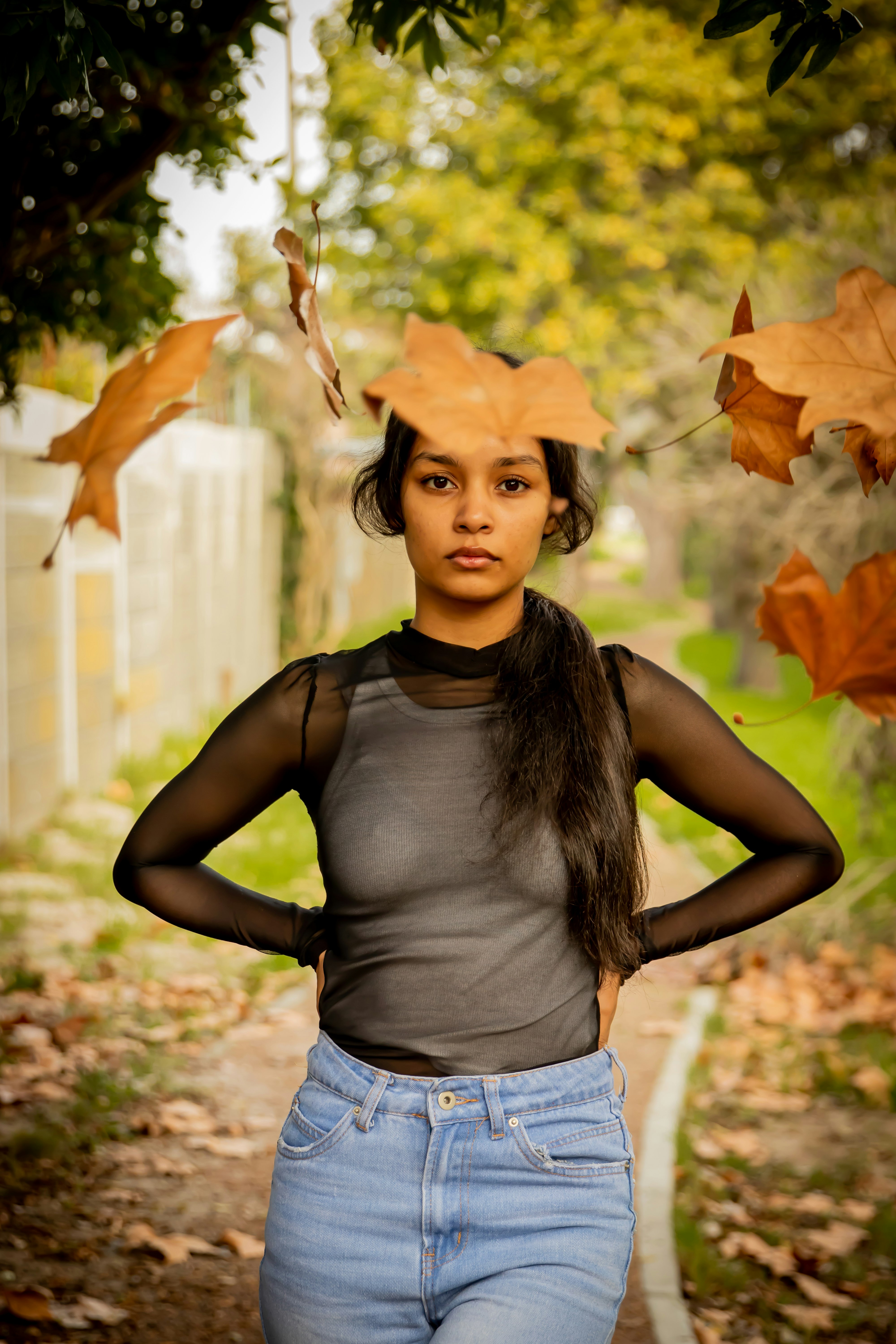 woman in black tank top and blue denim shorts standing on dried leaves during daytime